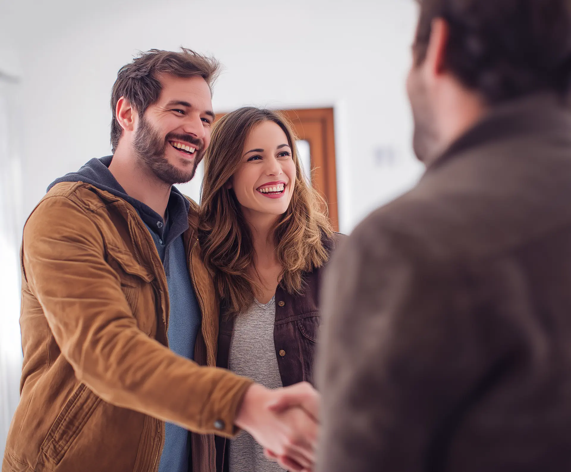 Glückliches Paar schüttelt Hände mit Immobilienmakler.